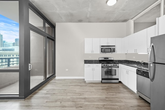 kitchen with appliances with stainless steel finishes, light wood-type flooring, and white cabinets