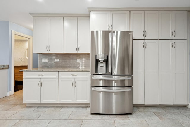 kitchen with white cabinetry, tasteful backsplash, stainless steel fridge with ice dispenser, and light stone counters