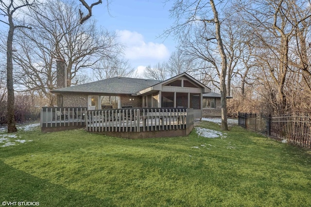 rear view of house with a lawn, a sunroom, and a deck