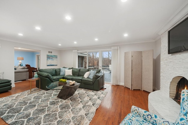 living room featuring hardwood / wood-style flooring, a fireplace, and ornamental molding