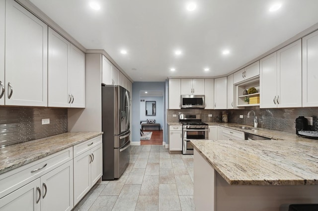 kitchen featuring stainless steel appliances, sink, white cabinets, and light stone counters