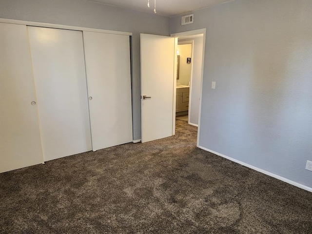 unfurnished bedroom with a closet and dark colored carpet