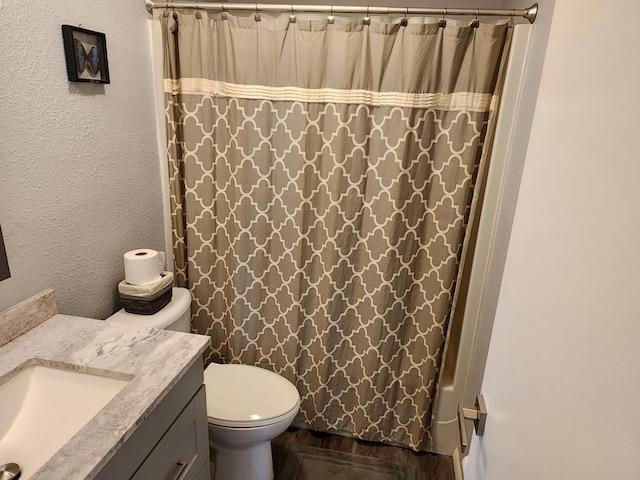 full bathroom with hardwood / wood-style flooring, shower / tub combo with curtain, vanity, and toilet