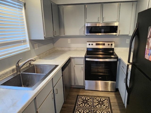 kitchen with gray cabinetry, sink, dark hardwood / wood-style floors, and appliances with stainless steel finishes