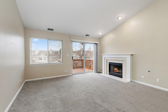 unfurnished living room with a tile fireplace, vaulted ceiling, and light carpet