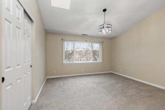 carpeted spare room with a notable chandelier