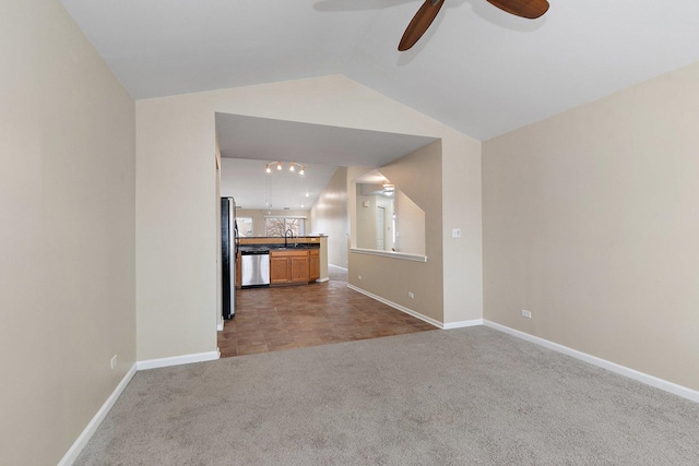 unfurnished living room featuring vaulted ceiling, ceiling fan, carpet flooring, and sink