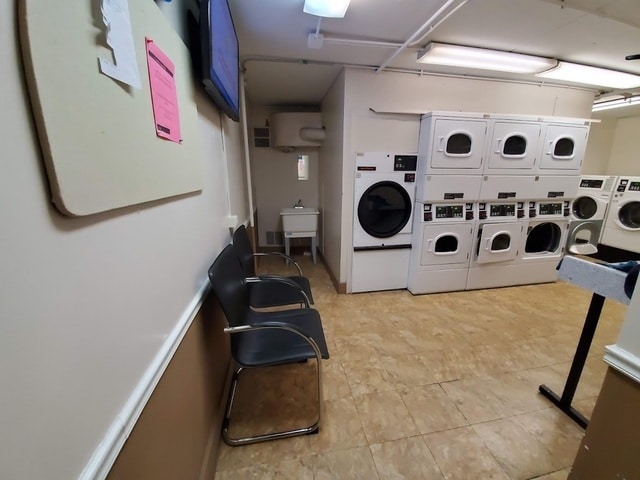 shared laundry area featuring a garage, stacked washing maching and dryer, washing machine and dryer, and a sink