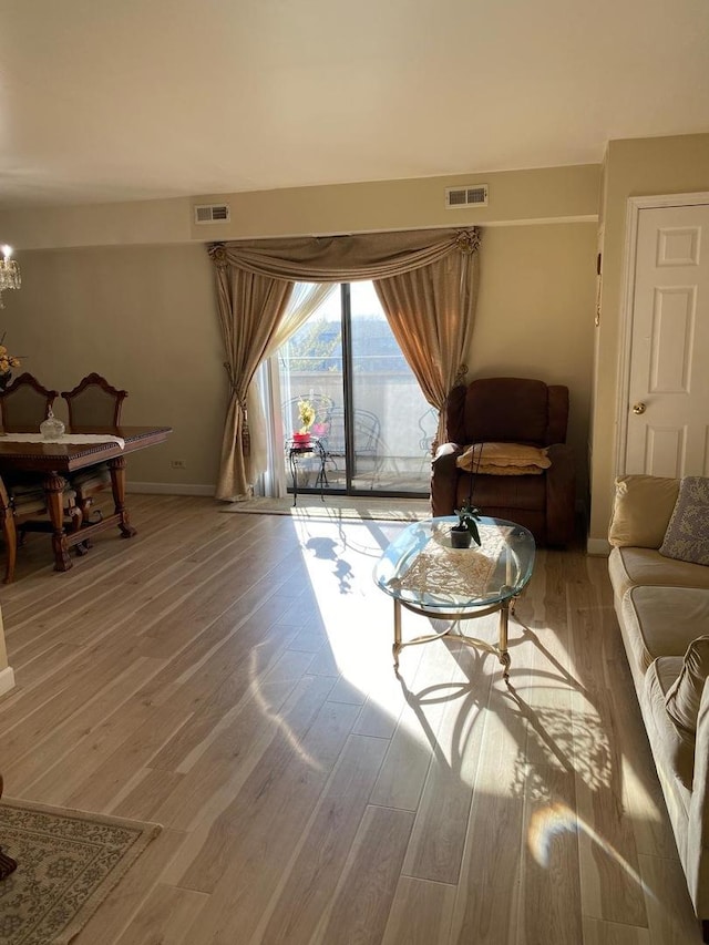 living room featuring an inviting chandelier, baseboards, visible vents, and wood finished floors