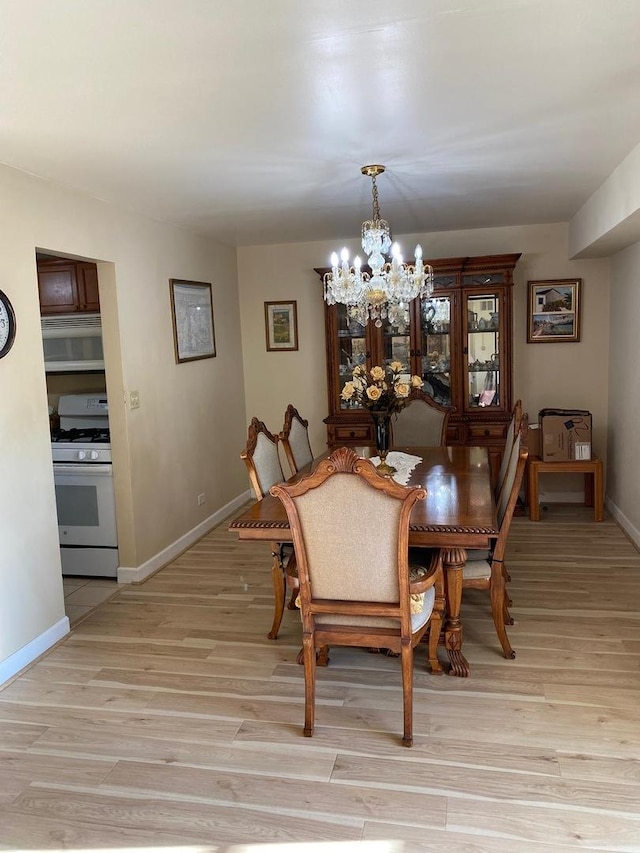 dining area with baseboards, light wood finished floors, and an inviting chandelier