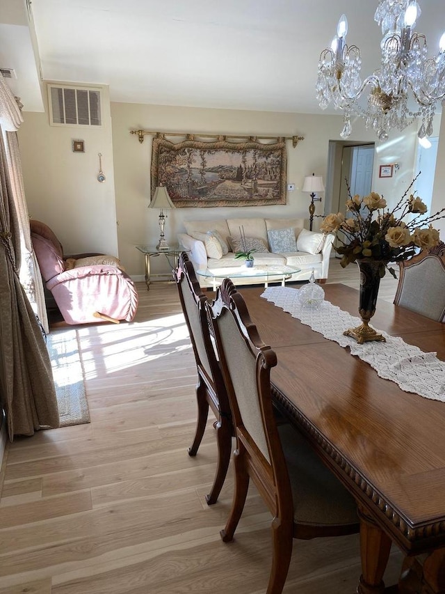 dining area featuring light wood-style floors, visible vents, baseboards, and an inviting chandelier