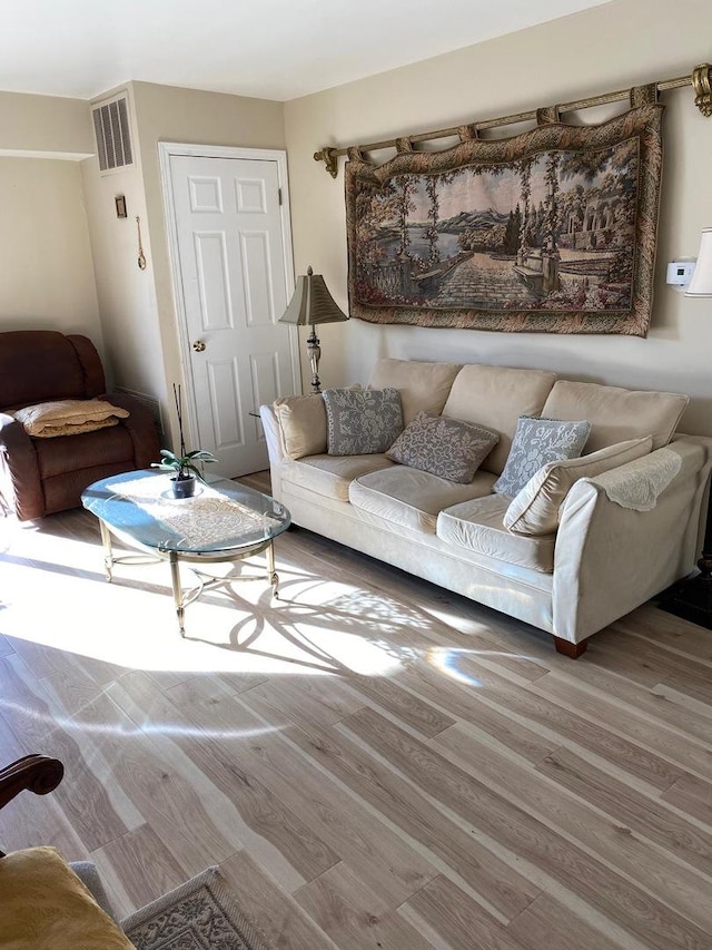 living area with visible vents and wood finished floors