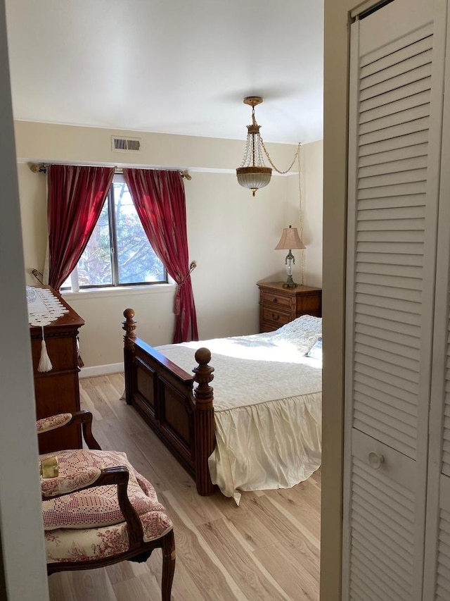 bedroom with light wood-type flooring, visible vents, and baseboards