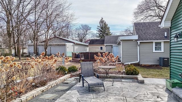 view of patio / terrace featuring cooling unit, a wooden deck, a garage, and an outbuilding