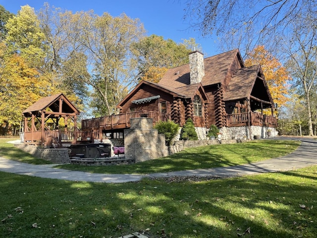 view of side of property with a gazebo, a lawn, and a hot tub