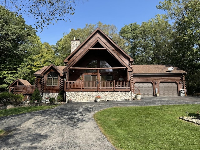 cabin with a garage, a deck, and a front lawn