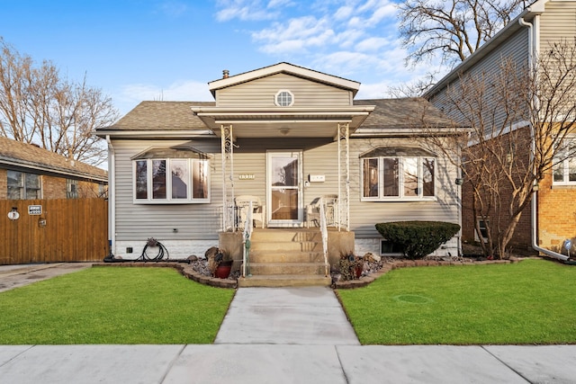 bungalow-style home with a shingled roof, a front yard, and fence