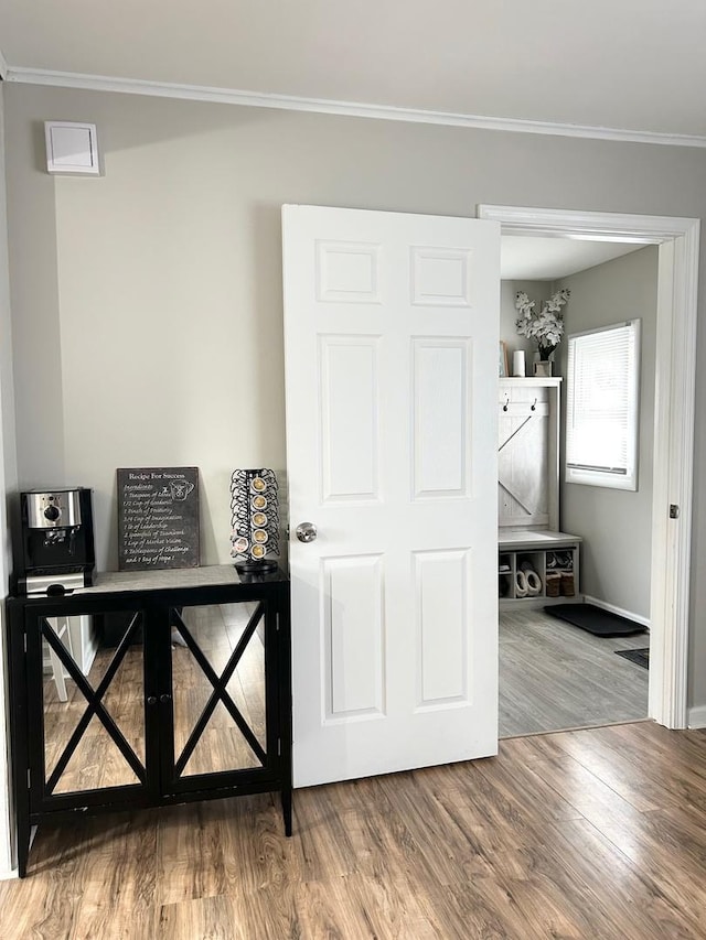 hall with wood-type flooring and ornamental molding