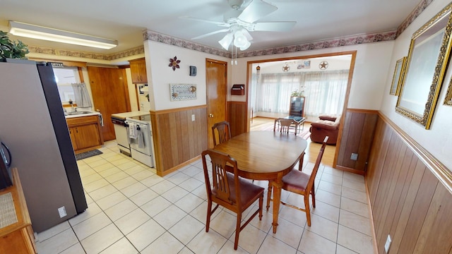 tiled dining space with sink, wooden walls, and ceiling fan