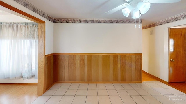 unfurnished room featuring ceiling fan and wood walls