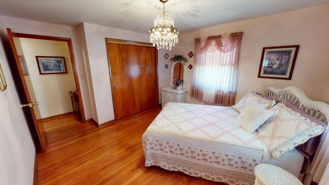 bedroom with hardwood / wood-style floors, a closet, and a notable chandelier