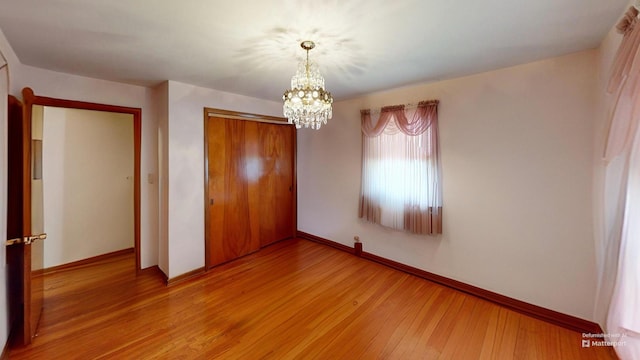 unfurnished bedroom with a chandelier, light hardwood / wood-style floors, and a closet