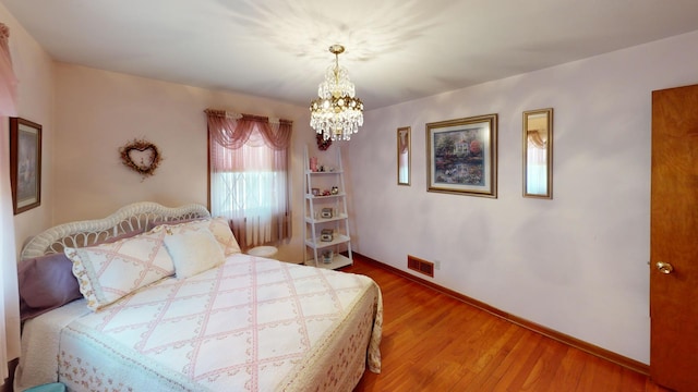 bedroom with an inviting chandelier and wood-type flooring