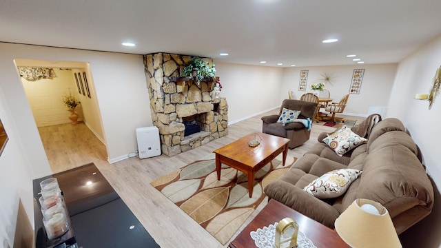 living room with hardwood / wood-style flooring and a stone fireplace