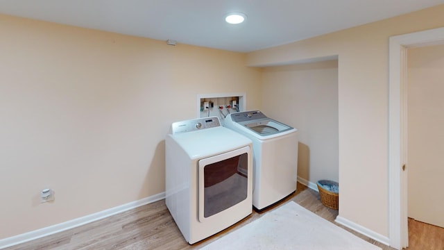 laundry room with washer and clothes dryer and light hardwood / wood-style flooring