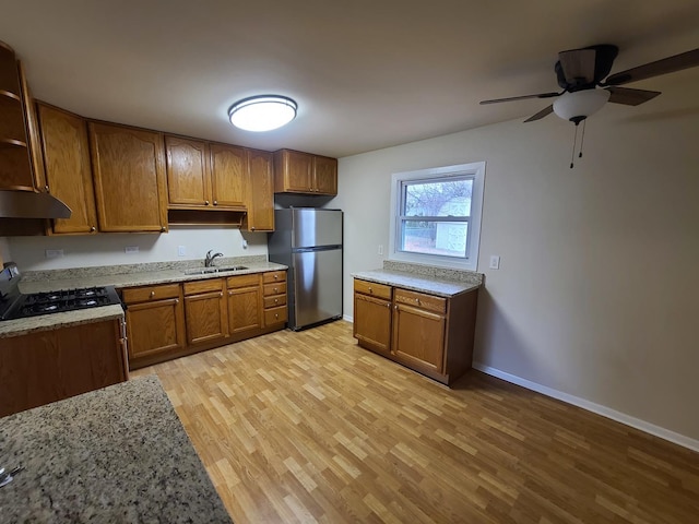 kitchen featuring sink, range with gas cooktop, light hardwood / wood-style flooring, stainless steel refrigerator, and ceiling fan