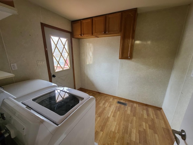 clothes washing area featuring cabinets, washer and clothes dryer, and light wood-type flooring