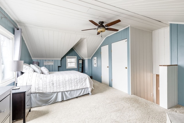 carpeted bedroom featuring vaulted ceiling, ceiling fan, and wood walls