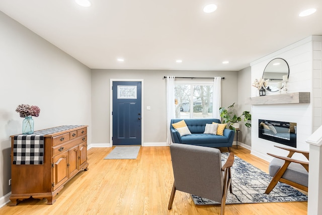 living room featuring light hardwood / wood-style floors and a large fireplace