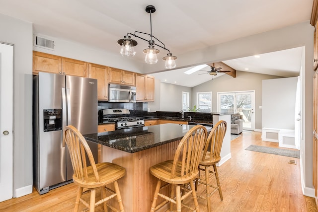 kitchen featuring stainless steel appliances, hanging light fixtures, light hardwood / wood-style flooring, and vaulted ceiling with beams