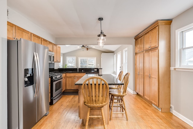 kitchen with sink, appliances with stainless steel finishes, a kitchen island, a kitchen bar, and vaulted ceiling