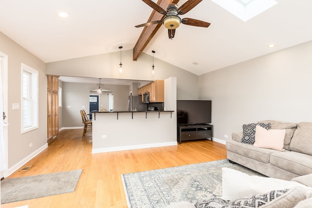 living room with lofted ceiling with skylight, ceiling fan, and light hardwood / wood-style flooring