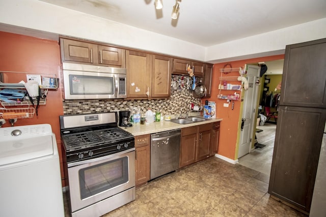 kitchen featuring stainless steel appliances, washer / clothes dryer, sink, and backsplash