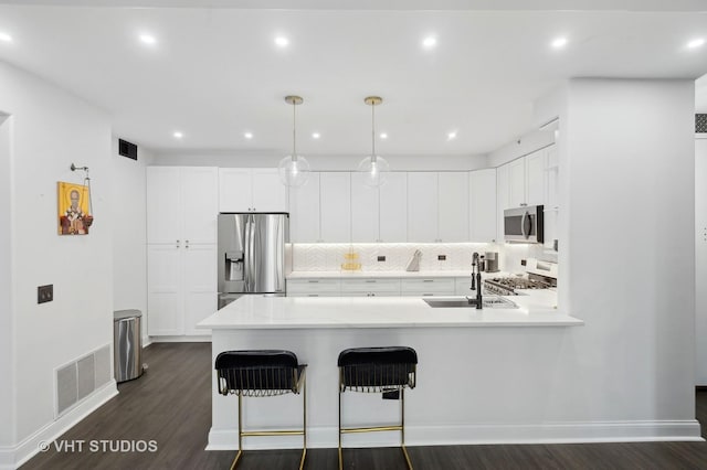 kitchen featuring appliances with stainless steel finishes, sink, pendant lighting, and white cabinets