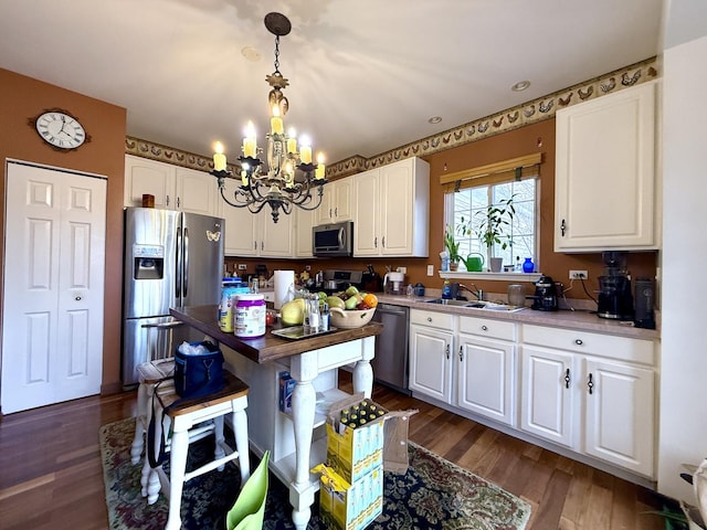 kitchen with pendant lighting, sink, dark wood-type flooring, appliances with stainless steel finishes, and white cabinets