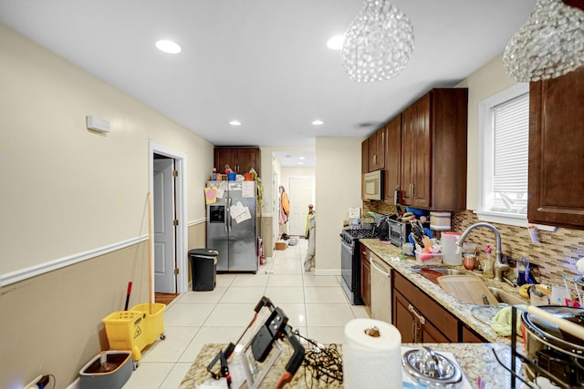 kitchen featuring stainless steel appliances, sink, light stone counters, and decorative backsplash