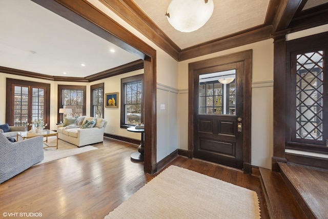 foyer entrance with wood-type flooring, ornamental molding, and french doors