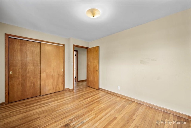 unfurnished bedroom with hardwood / wood-style flooring, baseboards, and a closet