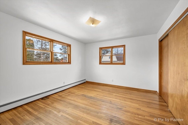 unfurnished bedroom featuring light wood-style floors, a closet, baseboards, and baseboard heating