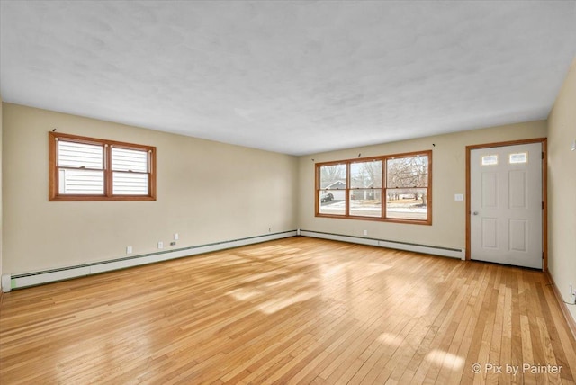 interior space featuring a healthy amount of sunlight, light wood-type flooring, and baseboard heating