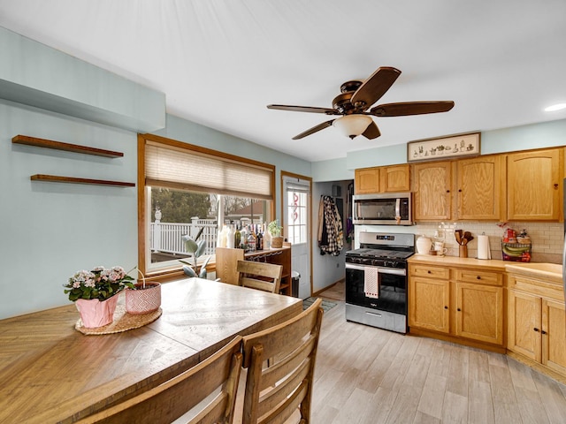 kitchen with ceiling fan, appliances with stainless steel finishes, light hardwood / wood-style floors, and decorative backsplash