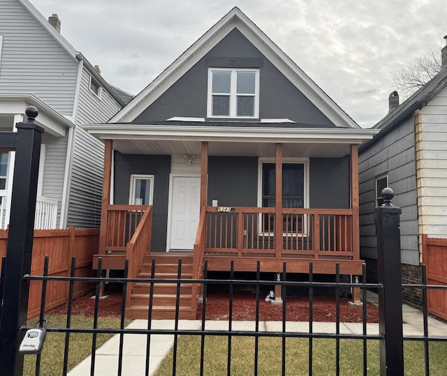 bungalow with brick siding, covered porch, and fence