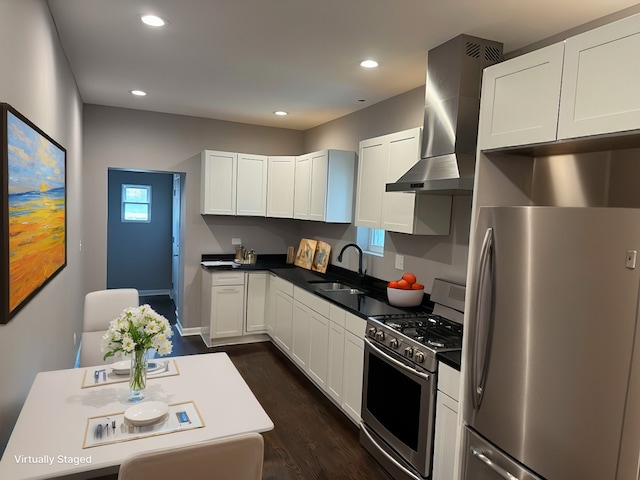 kitchen featuring a sink, stainless steel appliances, white cabinetry, dark countertops, and wall chimney range hood