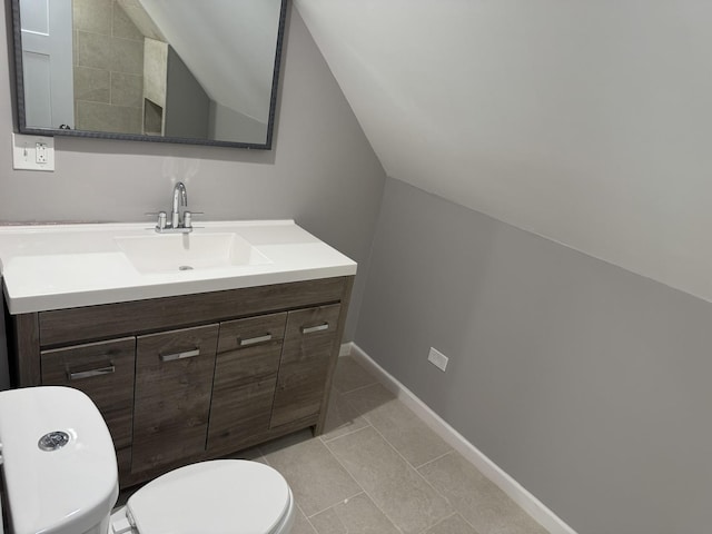 bathroom with tile patterned flooring, vanity, lofted ceiling, and toilet