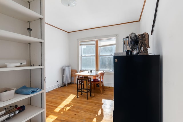 dining area featuring hardwood / wood-style flooring, crown molding, and radiator heating unit