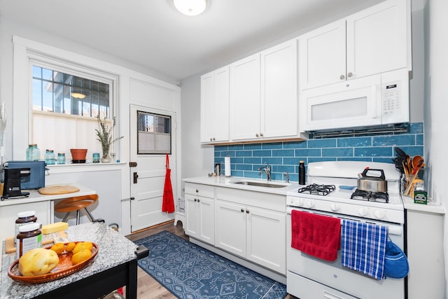 kitchen featuring sink, white cabinetry, white appliances, hardwood / wood-style floors, and decorative backsplash